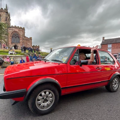 a vehicle in the parade passes st james 39  church in audlem