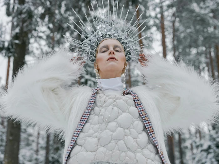 a woman with a crown wearing white dress and fur coat