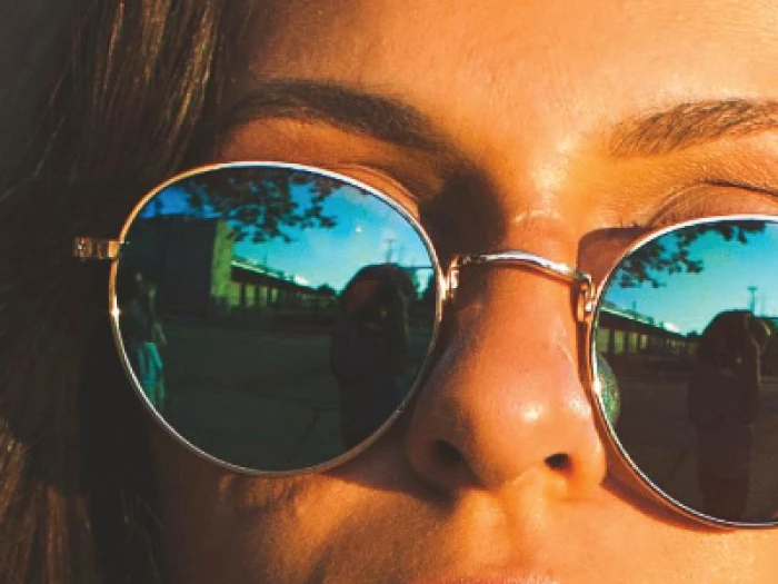 Woman with gold-rimmed reflective sunglasses