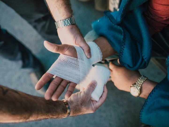 Person Applying Bandage on Another Person's Hand