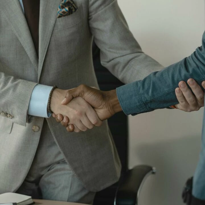 Image of a professional handshake between two businessmen in an office setting.